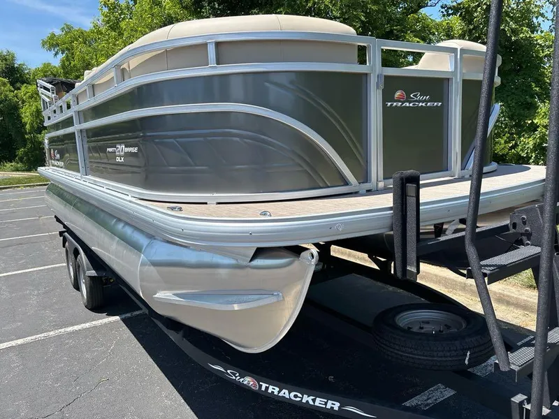 Slide: The Image of 2024 Sun Tracker Party Barge 20 DLX pontoon boat on trailer in parking lot. - 2