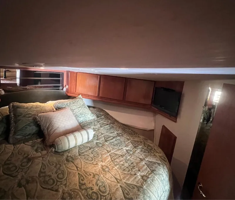 Slide: The Image of 2001 Egg Harbor 37 Convertible cabin with bed, pillows, and wooden cabinets. - 18