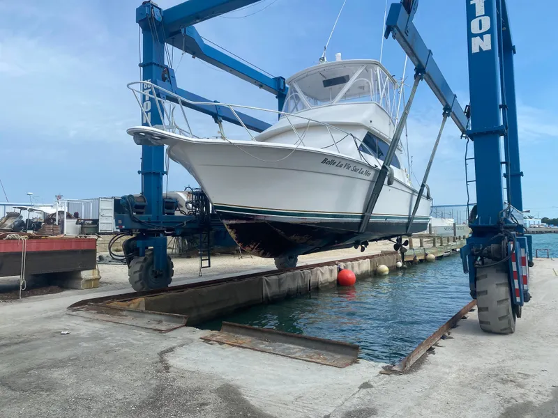 Slide: The Image of 2001 Egg Harbor 37 Convertible boat being lifted from water by a blue crane. - 2