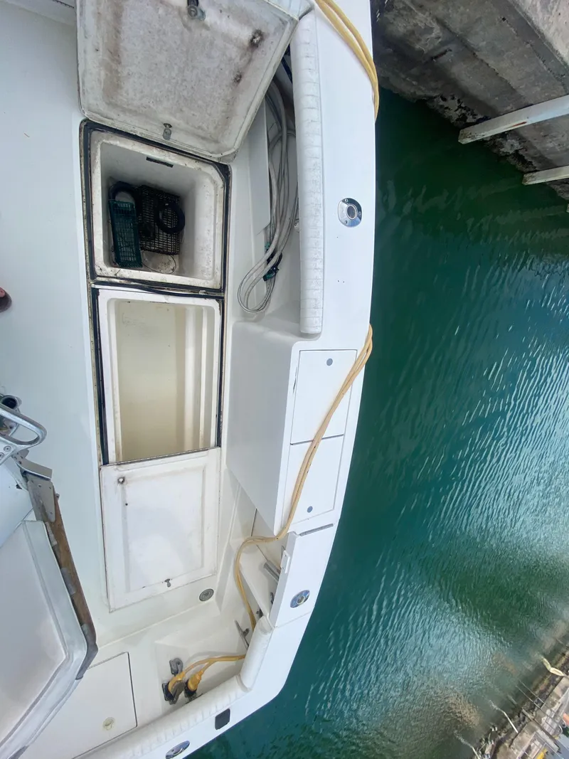 Slide: The Image of 2001 Egg Harbor 37 Convertible boat docked, showing open storage compartments and clean deck. - 7