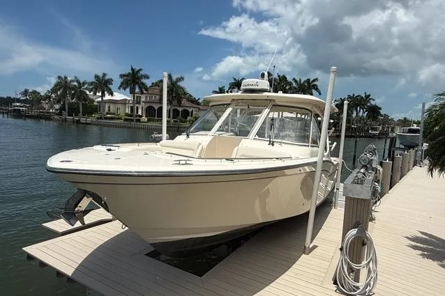 Slide: The Image of 2018 Grady-White Freedom 325 boat docked by waterfront homes under a partly cloudy sky. - 20