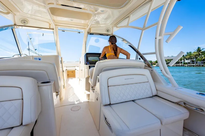 Slide: The Image of 2018 Grady-White Freedom 335 interior with woman at helm, cruising on clear waters. - 4