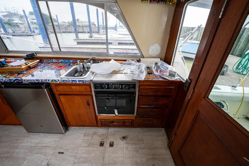 Slide: The Image of 1984 Bertram 33 Sport Fisherman boat kitchen with sink, stove, and wooden cabinets. - 14