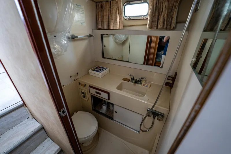 Slide: The Image of 1984 Bertram 33 Sport Fisherman bathroom with sink, toilet, mirror, and storage. - 18
