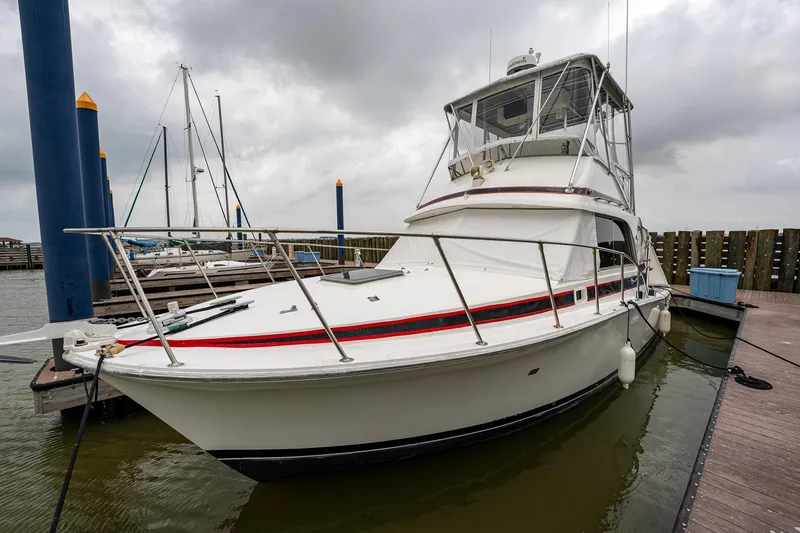 Slide: The Image of 1984 Bertram 33 Sport Fisherman docked at a marina under cloudy skies. - 3