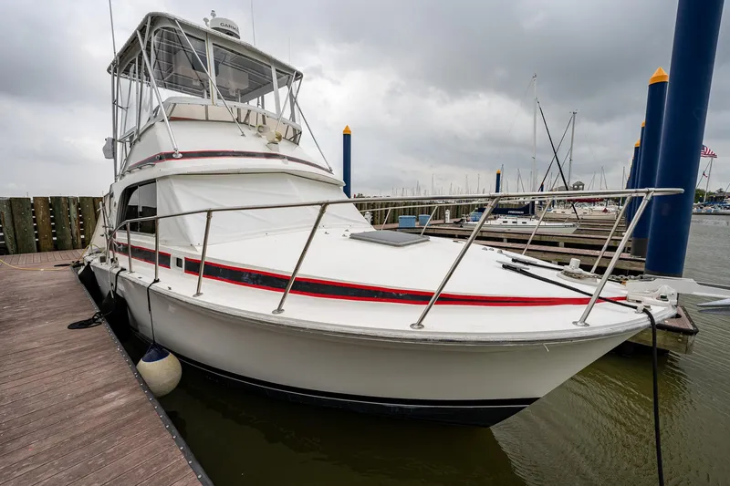 Slide: The Image of 1984 Bertram 33 Sport Fisherman boat docked at marina on a cloudy day. - 4
