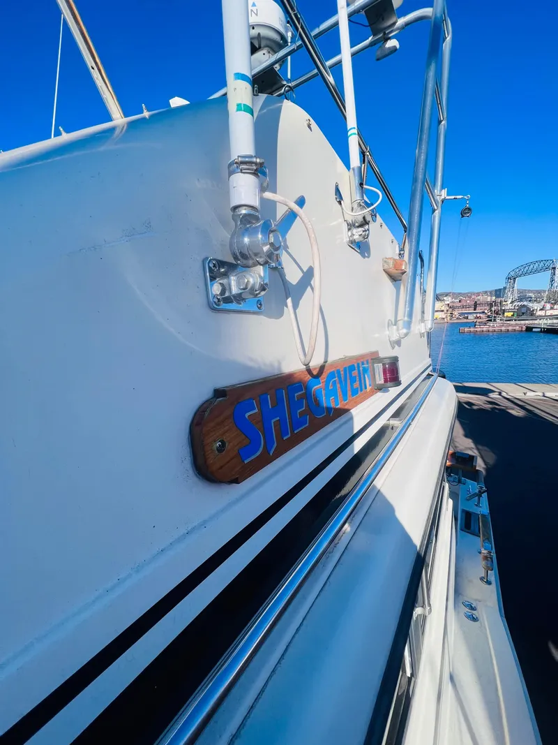 Slide: The Image of 1976 Trojan F 32 boat docked, featuring "SHEGAVEIN" nameplate, clear blue sky background. - 4