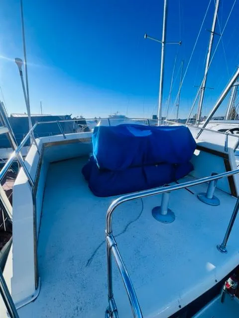 Slide: The Image of 1976 Trojan F 32 boat deck with blue cover under clear sky. - 5