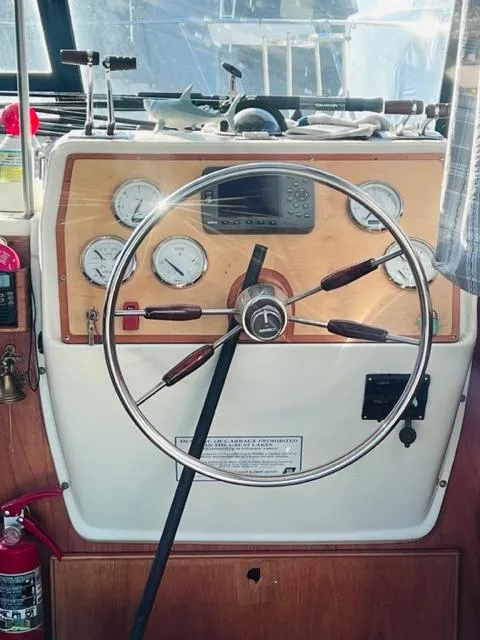 Slide: The Image of Steering wheel and dashboard of a 1976 Trojan F 32 boat, featuring gauges and controls. - 8