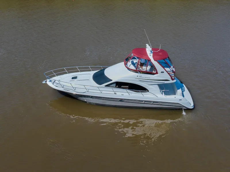 Slide: The Image of 2005 Sea Ray 420 Sedan Bridge yacht with red canopy on calm water. - 1