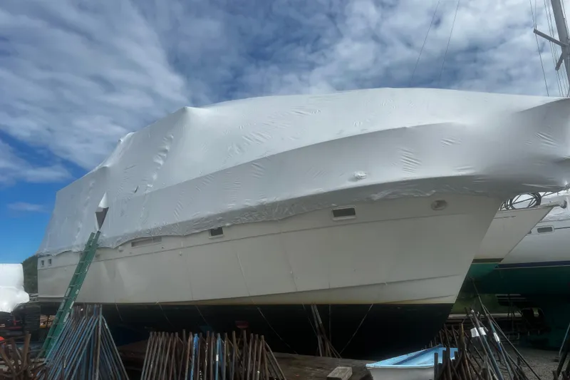 Slide: The Image of 1981 Hatteras 48 Motor Yacht covered in protective wrap, docked under a cloudy sky. - 25