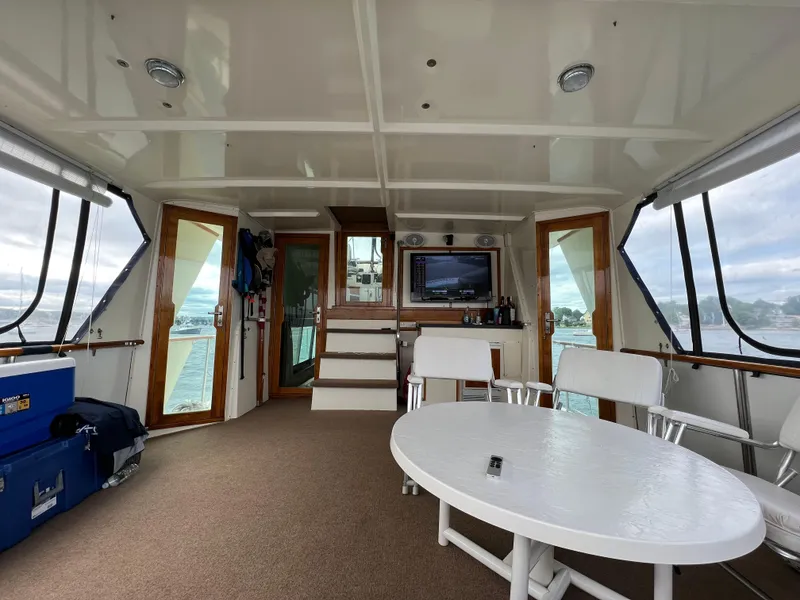 Slide: The Image of 1981 Hatteras 48 Motor Yacht interior with seating, table, and TV, overlooking water. - 6