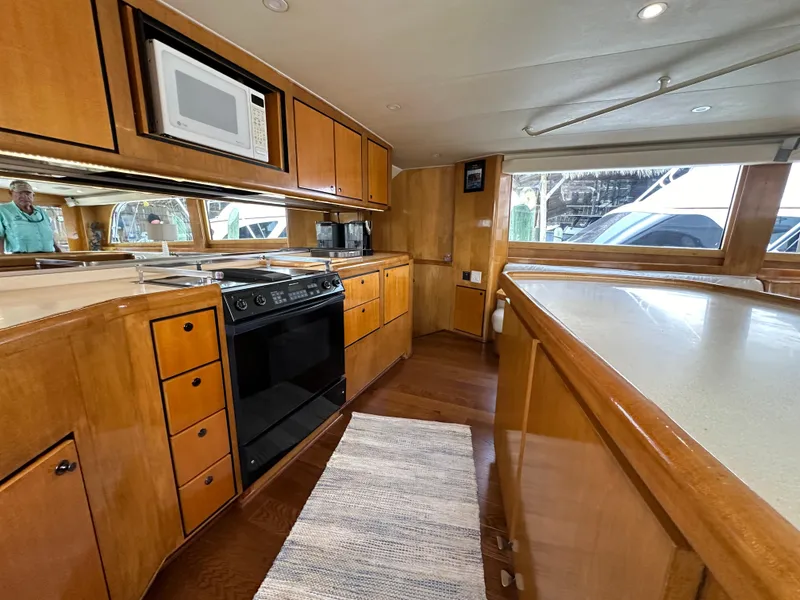 Slide: The Image of 1996 Donzi Custom Enclosed Flybridge kitchen with wooden cabinets, stove, microwave, and ample counter space. - 48