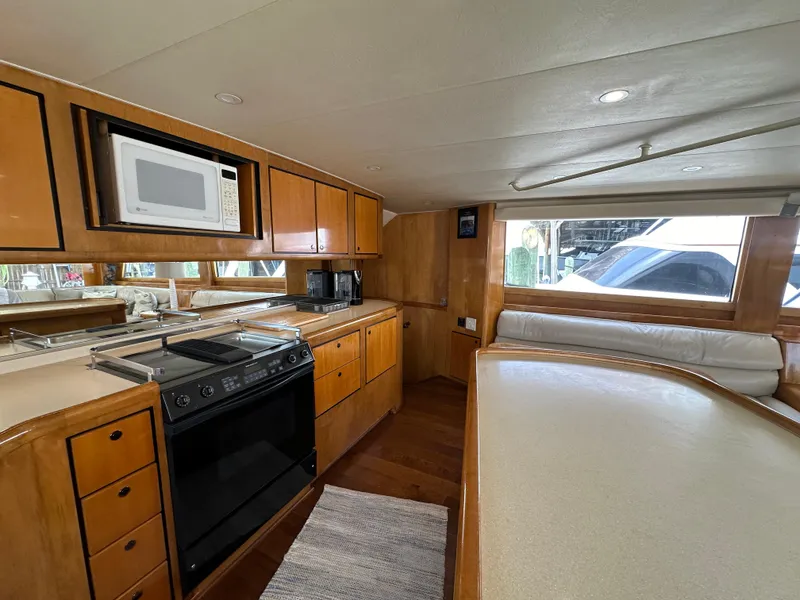 Slide: The Image of 1996 Donzi Custom Enclosed Flybridge kitchen with microwave, stove, and wooden cabinetry. - 49
