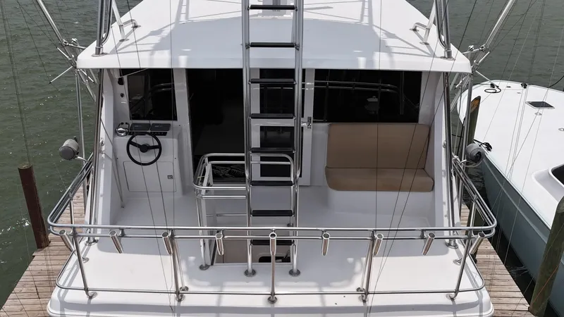 Slide: The Image of 1996 Donzi Custom Enclosed Flybridge yacht docked, rear view showing ladder and seating area. - 5