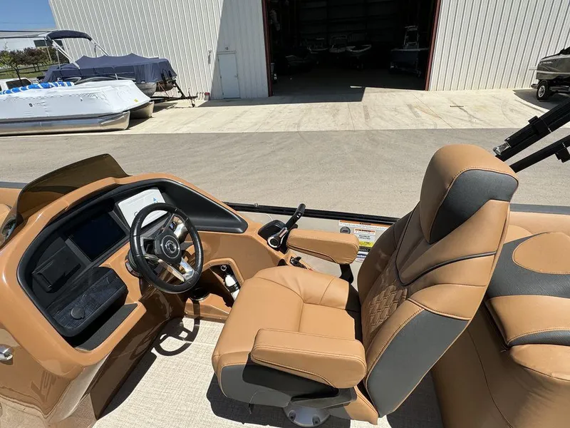 Slide: The Image of 2024 Tahoe Cascade 2385 EL boat interior with tan and gray captain's chair and steering console. - 16