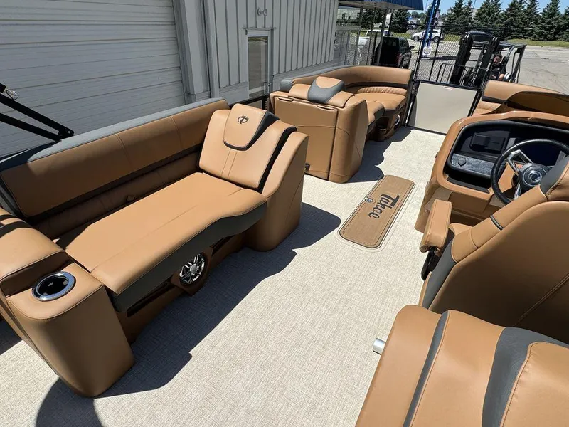 Slide: The Image of 2024 Tahoe Cascade 2385 EL boat interior with tan leather seating and modern dashboard. - 19