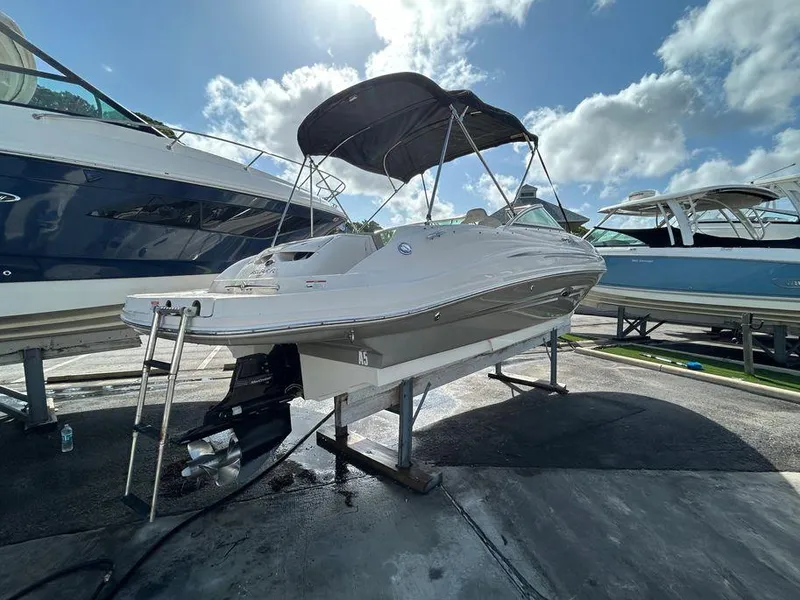 Slide: The Image of 2007 Sea Ray 220 Sundeck boat on a lift, with a black canopy, in a marina. - 14