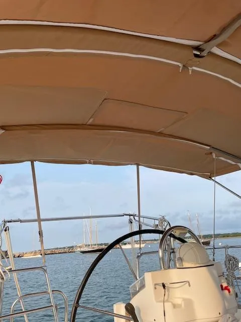 Slide: The Image of 2005 Beneteau 423 sailboat cockpit with steering wheel and canopy, docked in a marina. - 10