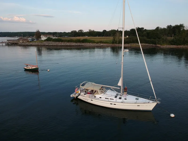 Slide: The Image of 2005 Beneteau 423 sailboat anchored in calm waters near a scenic shoreline. - 6