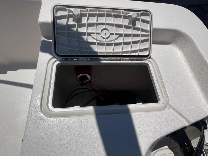 Slide: The Image of 2024 Carolina Skiff EV198 storage compartment with open lid. - 12