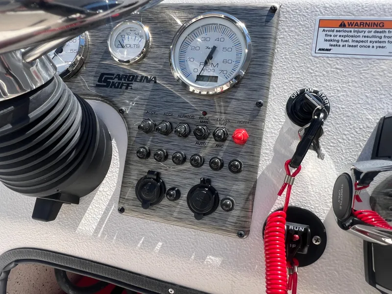 Slide: The Image of Control panel of a 2024 Carolina Skiff EV198 boat with gauges and switches. - 13
