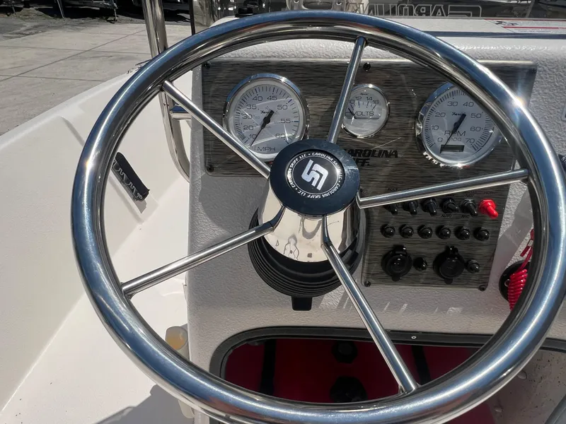 Slide: The Image of 2024 Carolina Skiff EV198 boat steering wheel and dashboard controls. - 16