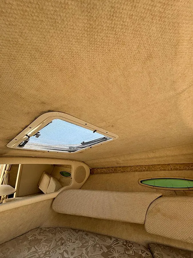 Slide: The Image of Interior cabin of 2003 Sea Ray 225 Weekender with skylight and beige upholstery. - 25