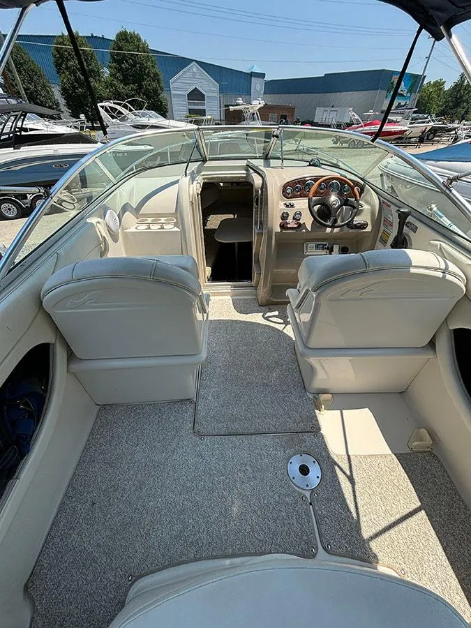 Slide: The Image of 2003 Sea Ray 225 Weekender boat interior with helm, seating, and cabin entrance. - 9