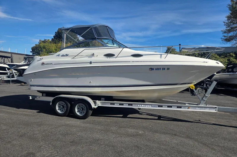 The Image of 1998 Sea Ray 240 Sundancer boat on trailer, parked outdoors under clear blue sky. - 0