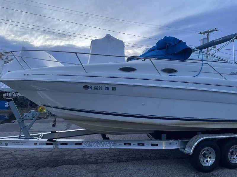Slide: The Image of 1998 Sea Ray 240 Sundancer boat on trailer, parked outdoors under clear sky. - 3