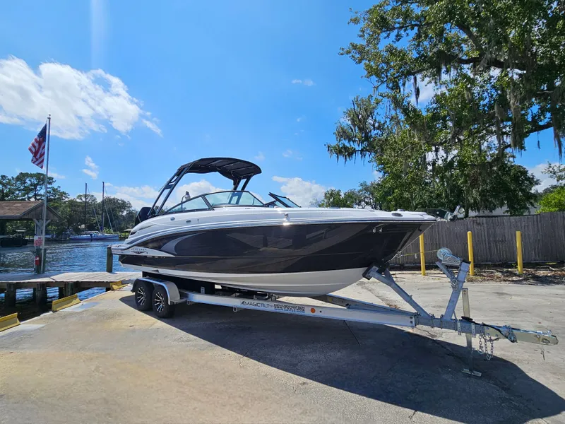 Slide: The Image of 2025 Monterey M-65 boat on trailer by waterfront, under clear blue sky. - 2