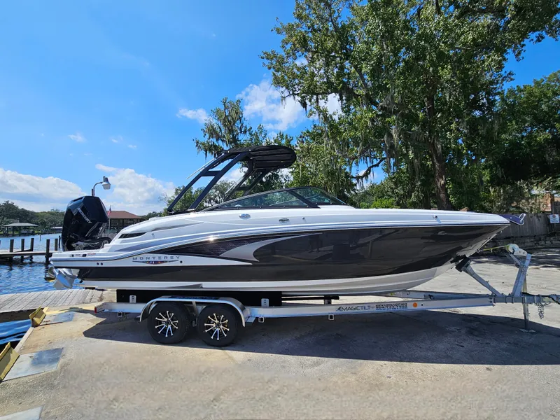 Slide: The Image of 2025 Monterey M-65 boat on trailer by waterfront, under clear blue sky. - 3