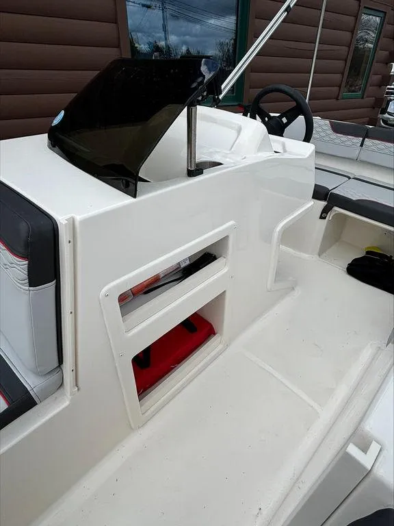 Slide: The Image of 2023 Bayliner 170 EL boat interior with storage compartments and steering console. - 9