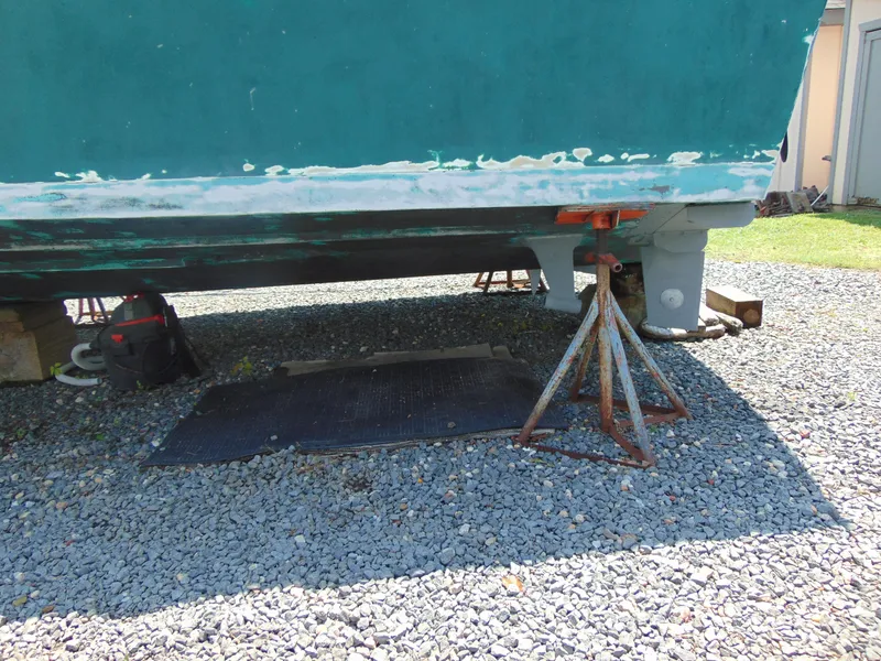 Slide: The Image of 1987 Black Watch Sportfish boat on stands, undergoing maintenance on gravel surface. - 11