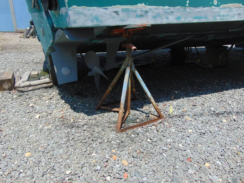 Slide: The Image of 1987 Black Watch Sportfish boat on gravel, supported by a rusty metal stand. - 13