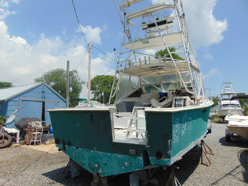 Slide: The Image of 1987 Black Watch Sportfish boat on dry dock, showing wear, with blue sky background. - 14