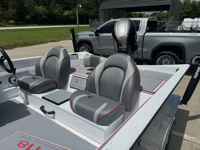 Slide: The Image of 2024 Xpress Boats H18 with gray and red seating, parked near a silver pickup truck. - 12