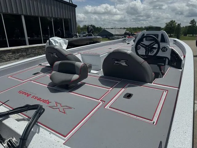 Slide: The Image of 2024 Xpress Boats H18 fishing boat with grey and red deck, dual seats, and steering console. - 3