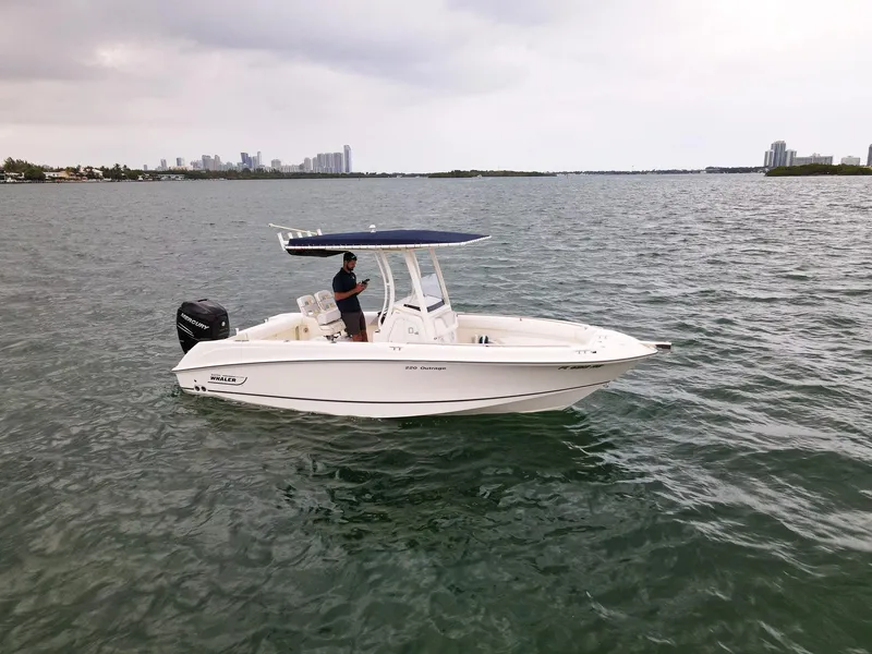 Slide: The Image of 2015 Boston Whaler 220 Outrage boat on open water with city skyline in background. - 8