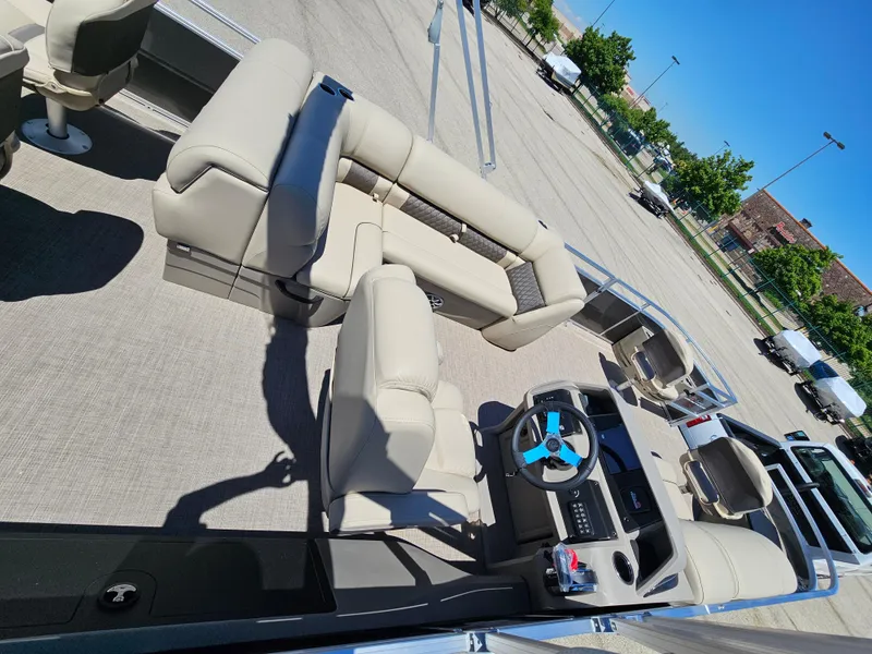 Slide: The Image of 2024 Sun Tracker Fishin' Barge 22 DLX interior with beige seating and steering console. - 2