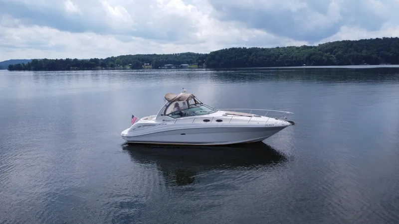 Slide: The Image of 2003 Sea Ray 340 Sundancer boat on a calm lake with scenic background. - 8