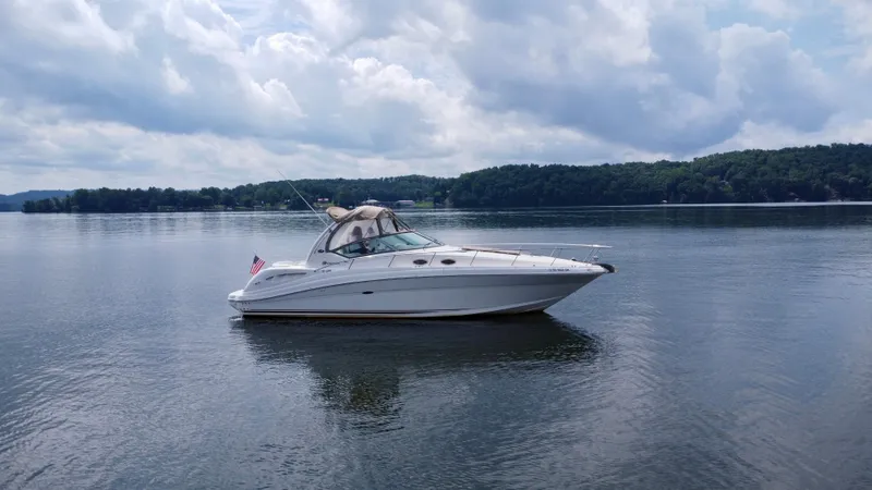 Slide: The Image of 2003 Sea Ray 340 Sundancer boat on a calm lake with cloudy sky. - 9