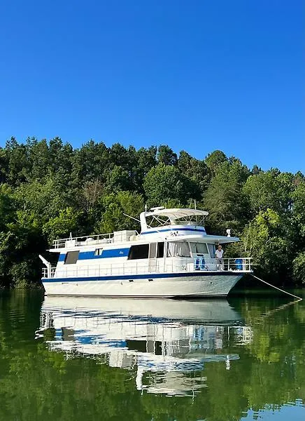 Slide: The Image of 1995 Pluckebaum Coastal Cruiser on calm water, surrounded by lush green trees. - 0