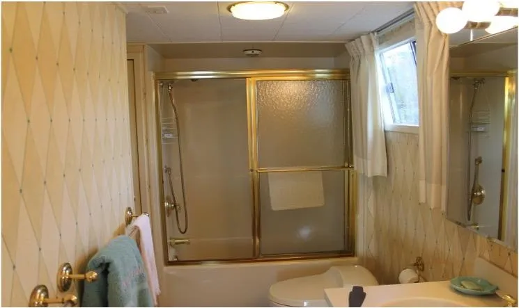 Slide: The Image of 1995 Pluckebaum Coastal Cruiser bathroom with shower, gold fixtures, and window. - 28