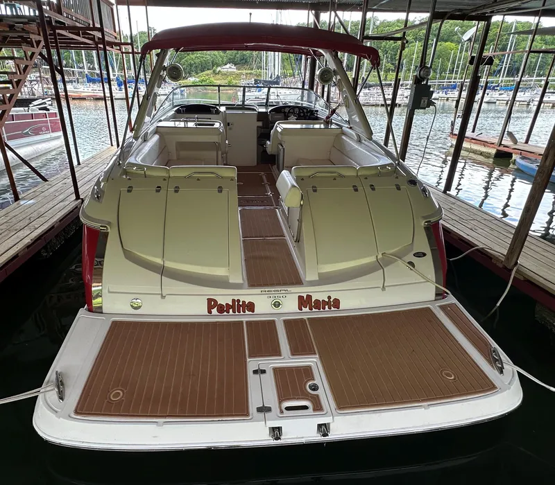 Slide: The Image of 2005 Regal 3350 Sport Cruiser docked, rear view with open seating area and red canopy. - 11