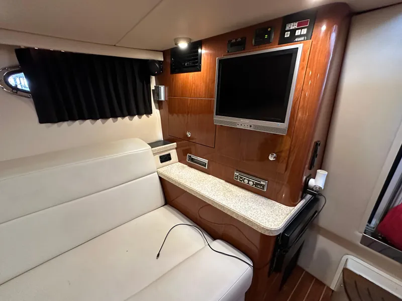 Slide: The Image of Interior of 2005 Regal 3350 Sport Cruiser with TV, white seating, and wood paneling. - 28