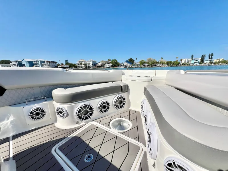 Slide: The Image of 2022 Sea Ray SLX 400 OB boat interior with seating and speakers, docked near waterfront homes. - 25