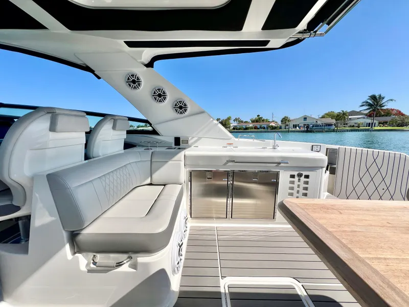 Slide: The Image of 2022 Sea Ray SLX 400 OB boat interior with seating, table, and kitchenette. - 8