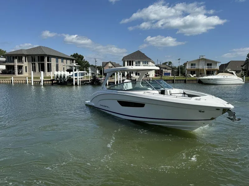 Slide: The Image of 2025 Regal 3300 boat cruising on a sunny waterfront with houses in the background. - 20